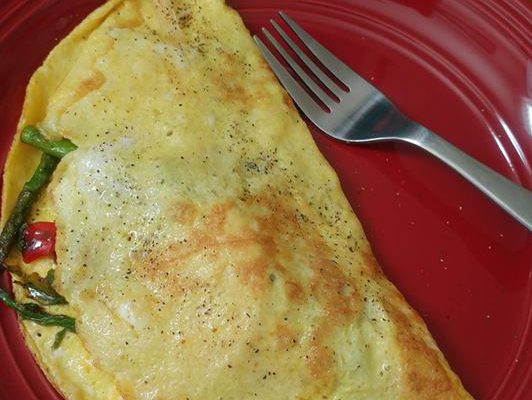 asparagus tomato omelette with a stainless steel fork on a red plate
