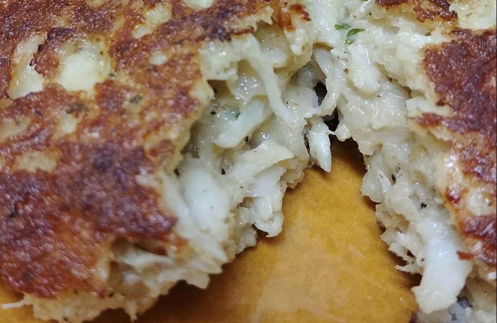 a crab cake split in half on a yellow plate