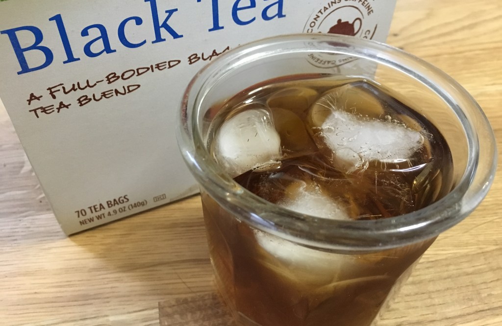 glass of iced tea in front of a box of bagged iced tea on a wooden surface