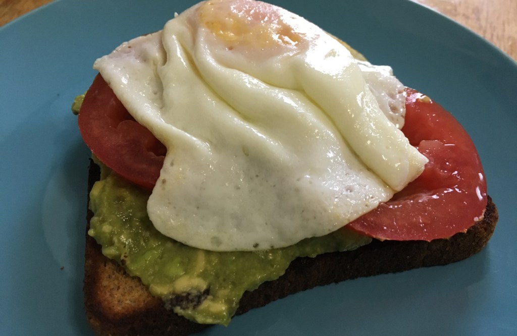 tomato avocado toast with eggs on a turquoise IKEA FÄRGRIK 8-inch side plate on a wooden surface